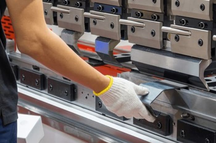 Operator folding sheet metal on the CNC press brake