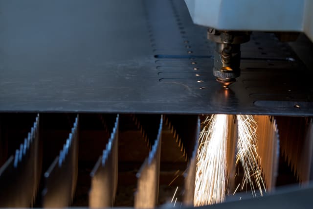 Fibre laser cutting a steel sheet, sparks trailing the cut